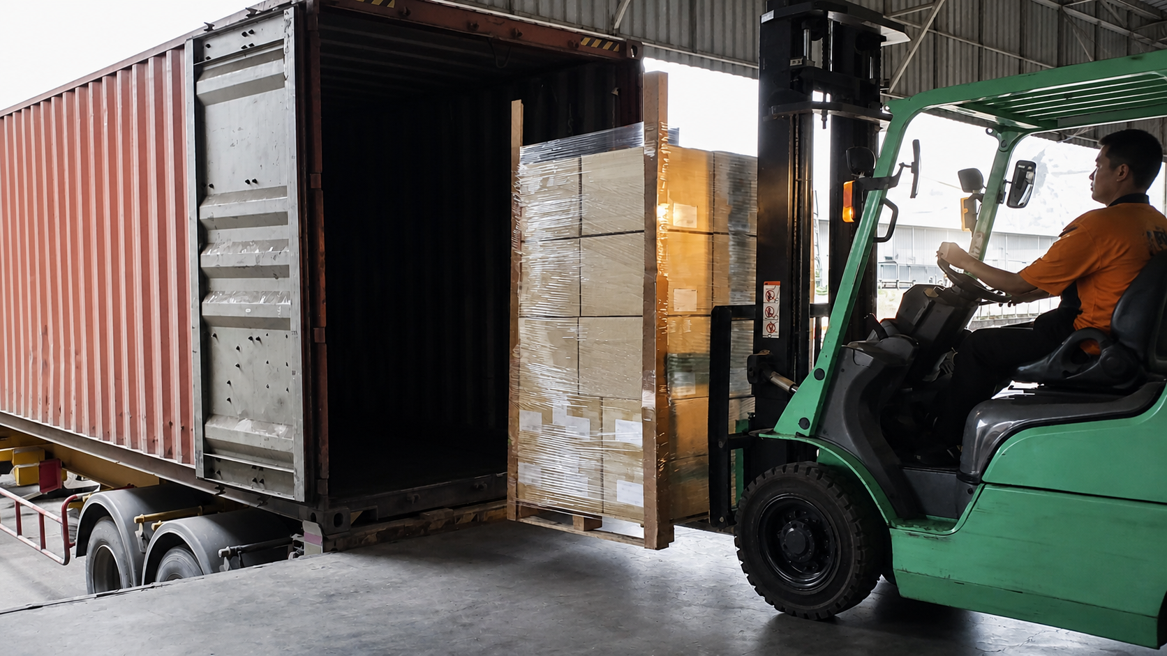 Forklift transferring palletized freight at a warehouse loading dock